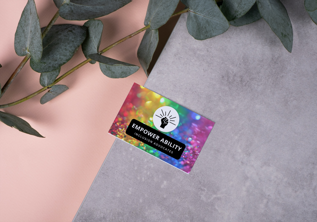 Rainbow Business Card on a gray surface near foliage.