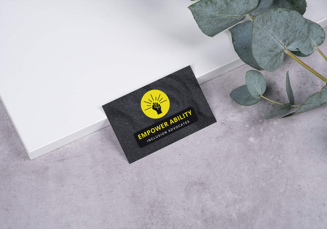 Yellow and gray Business Card on a gray surface near foliage.