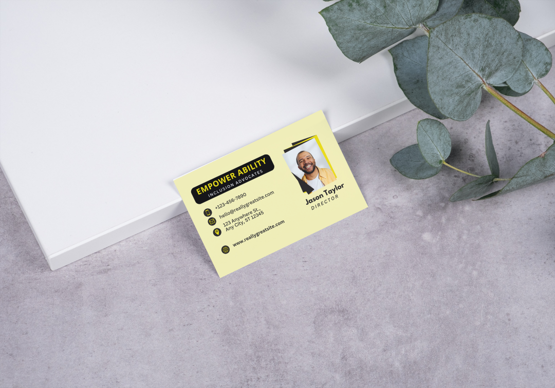 Yellow Business Card on a gray surface near foliage.