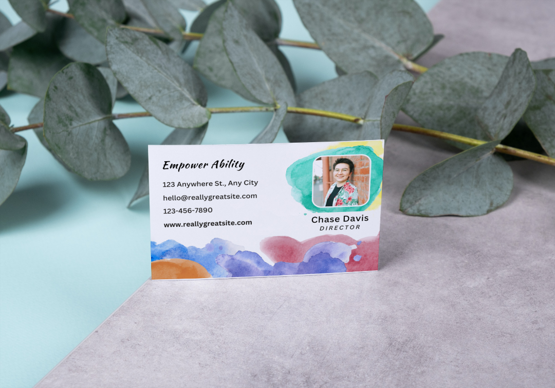 Watercolor Business Card on a gray surface near foliage.